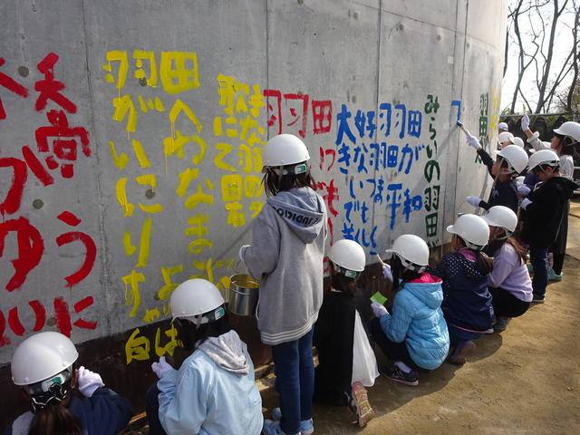 新小谷木橋下部工（P4橋脚）の基礎部に「未来の羽田地区に託す想い」をペイントする児童（4年生、6年生）の写真