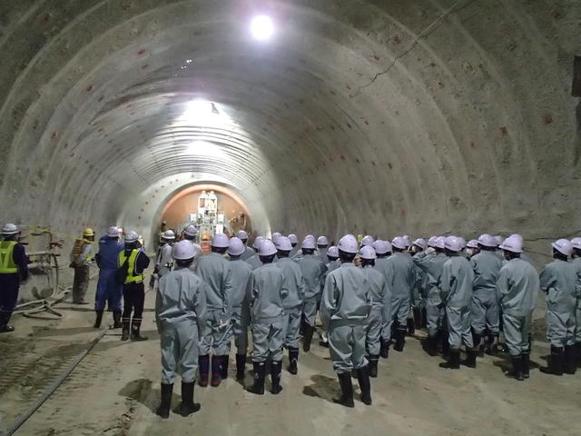 トンネル掘削機械（ドリルジャンボ）による岩盤削孔作業を見学する写真