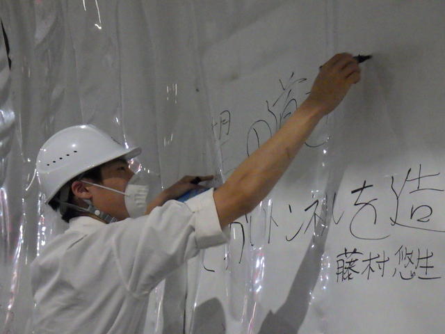 トンネルの防水シートに現場見学記念のメッセージを書込む一関工業高校の生徒の写真