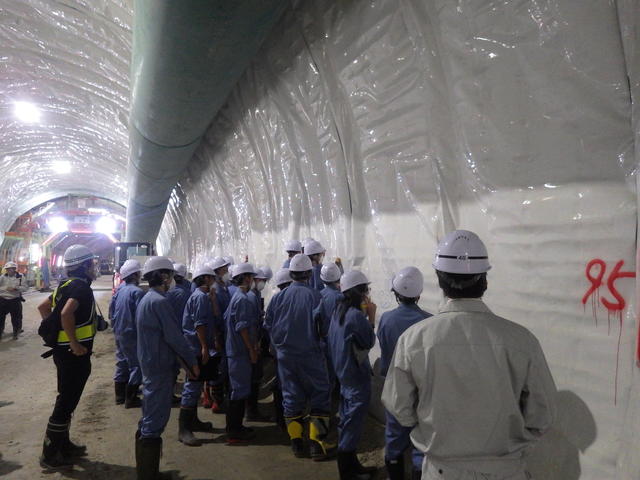 トンネルの防水シートに現場見学記念のメッセージを書込む盛岡工業高校の生徒たちの写真