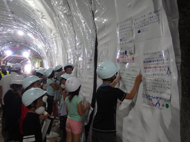 梁川小学校児童のメッセージ入り防水シートを貼り付けしている写真