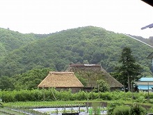 西和賀町沢内字川舟30地割付近の県道1号から見る茅葺きの古民家と付属の蔵と周辺の自然の景観