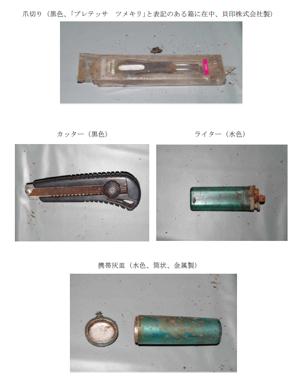 写真:爪切り(黒色、「プレテッサツメキリ」と表記のある箱に在中、貝印株式会社製)、カッター(黒色)、ライター(水色)、携帯灰皿(水色、筒状、金属製)